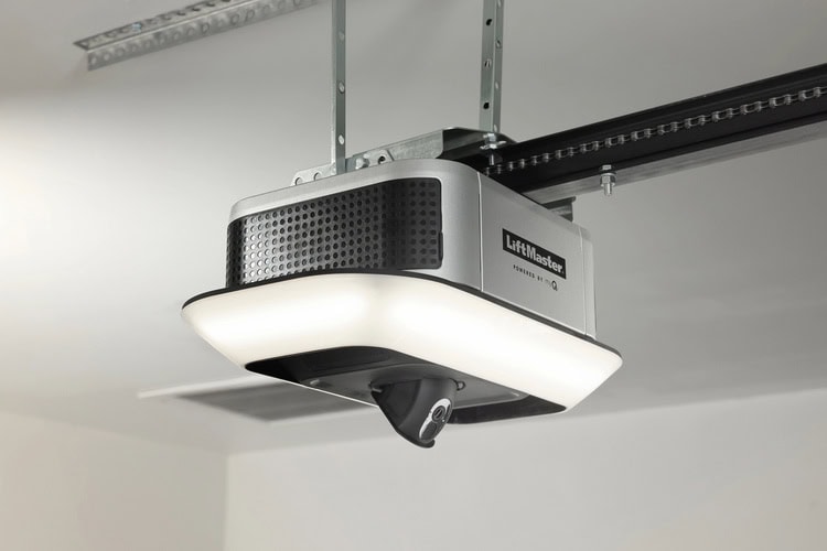 A garage door opener is mounted to the ceiling with a metal rail extending from it.